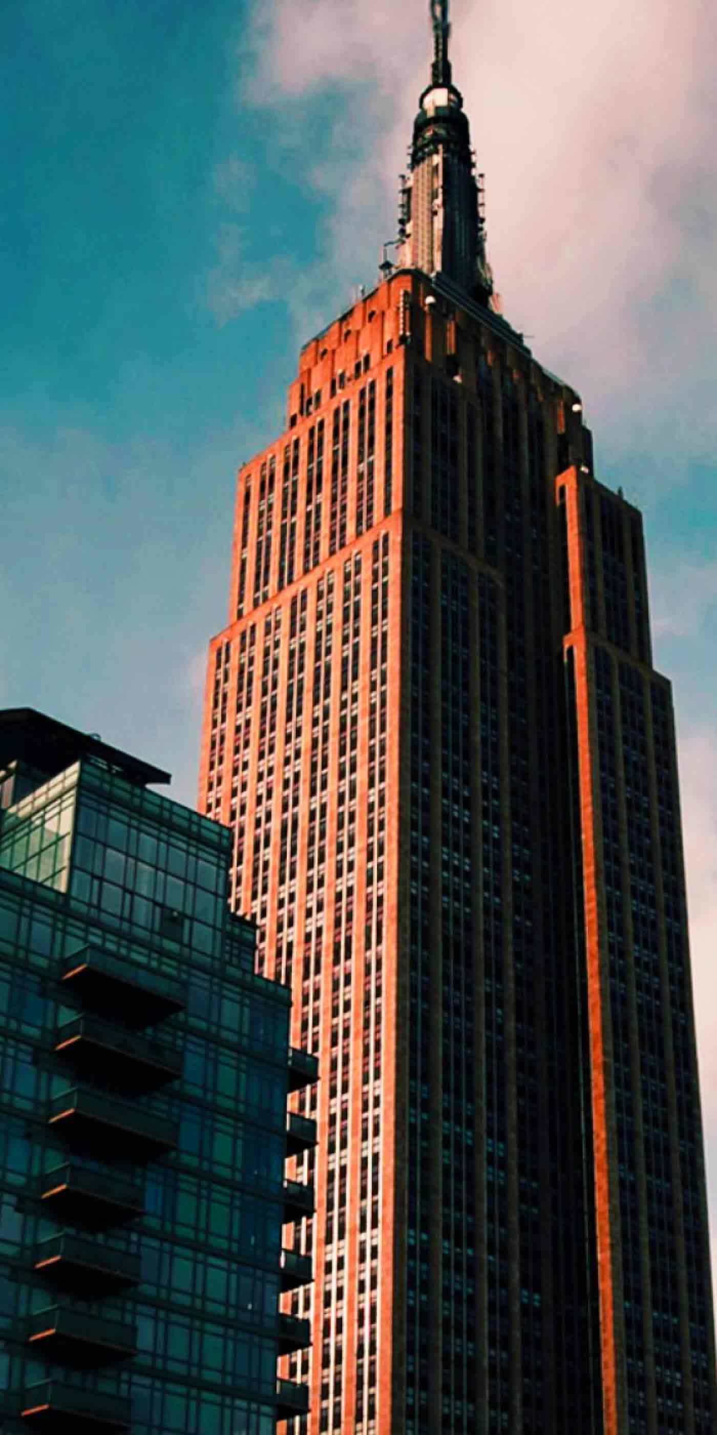 Empire State Building and nearby glass high-rises under a blue sky with pink clouds, representing StrawberryFrog's creative marketing & brand strategy offices in New York.