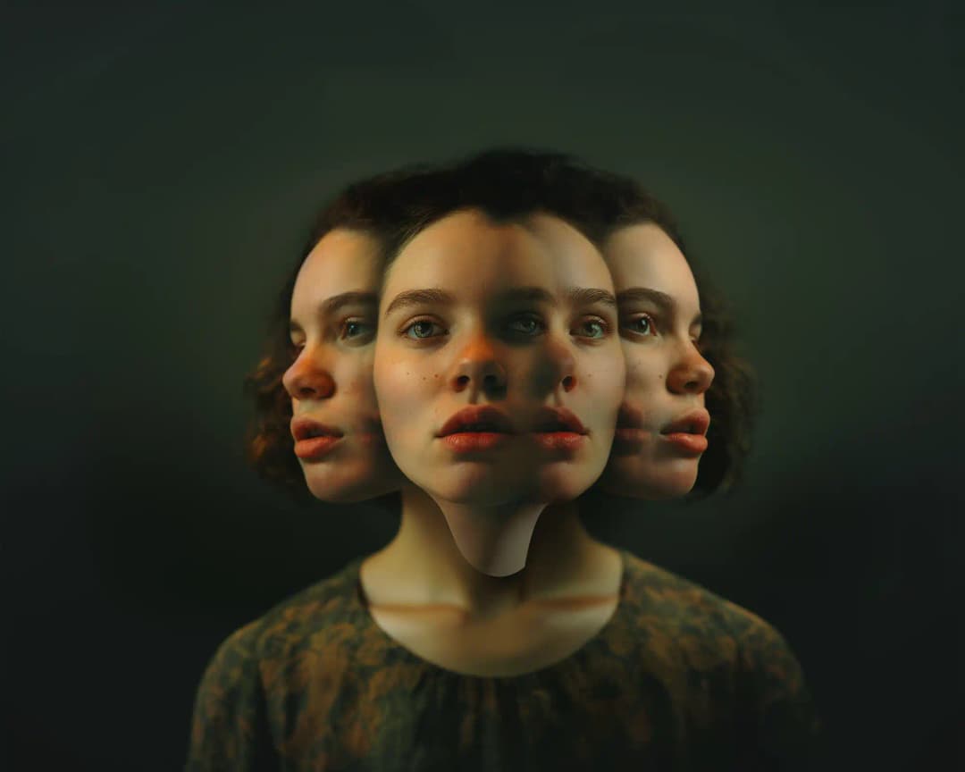 Woman's face with surreal multi-faceted effect showing three profiles merged into one head - central full face with light green eyes and reddish lips, flanked by two identical side profiles, all sharing one elongated neck against a dark greenish-gray background.